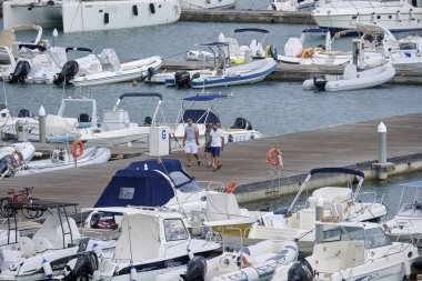 İtalya, Sicilya, Akdeniz, Marina di Ragusa (Ragusa Eyaleti); 3 Eylül 2019' da limanda insanlar, motorlu tekneler ve lüks yatlar - Editörden