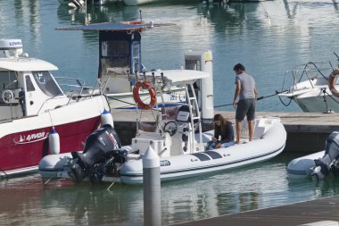 İtalya, Sicilya, Akdeniz, Marina di Ragusa (Ragusa Eyaleti); 13 Ekim 2019, limandaki kauçuk bir teknede yaşayan insanlar
