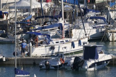 İtalya, Sicilya, Akdeniz, Marina di Ragusa (Ragusa Eyaleti); 17 Ekim 2019, limandaki bir yelkenli teknesindeki insanlar