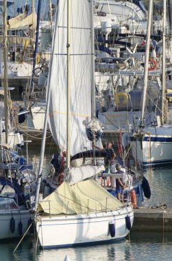 İtalya, Sicilya, Akdeniz, Marina di Ragusa (Ragusa Eyaleti); 19 Ekim 2019, limandaki bir yelkenli teknesindeki insanlar