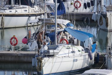 İtalya, Sicilya, Akdeniz, Marina di Ragusa (Ragusa Eyaleti); 21 Ekim 2019, limandaki bir yelkenli teknesinde adam