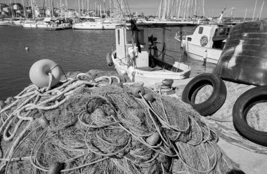 İtalya, Sicilya, Marina di Ragusa (Ragusa Eyaleti), ağlar, yerel ahşap balıkçı tekneleri ve limanda lüks yatlar