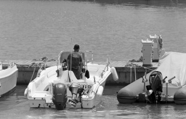 İtalya, Sicilya, Akdeniz, Marina di Ragusa (Ragusa Eyaleti); 19 Haziran 2020, limandaki bir motorlu teknede adam - EDITORIAL