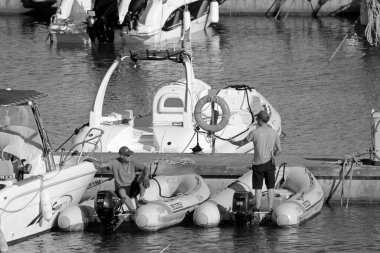 İtalya, Sicilya, Akdeniz, Marina di Ragusa (Ragusa Eyaleti); 25 Haziran 2020, limandaki kauçuk tekneler ve lüks yatlarda insanlar - EDITORIAL