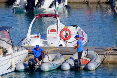 İtalya, Sicilya, Akdeniz, Marina di Ragusa (Ragusa Eyaleti); 25 Haziran 2020, limandaki kauçuk tekneler ve lüks yatlarda insanlar - EDITORIAL