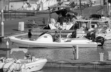 İtalya, Sicilya, Akdeniz, Marina di Ragusa (Ragusa Eyaleti); 28 Haziran 2020, büyük bir kauçuk bot ve limandaki lüks yatlardaki insanlar - EDITORIAL