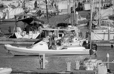 İtalya, Sicilya, Akdeniz, Marina di Ragusa (Ragusa Eyaleti); 28 Haziran 2020, büyük bir kauçuk bot ve limandaki lüks yatlardaki insanlar - EDITORIAL