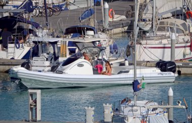 İtalya, Sicilya, Akdeniz, Marina di Ragusa (Ragusa Eyaleti); 28 Haziran 2020, büyük bir kauçuk bot ve limandaki lüks yatlardaki insanlar - EDITORIAL
