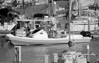 İtalya, Sicilya, Akdeniz, Marina di Ragusa (Ragusa Eyaleti); 28 Haziran 2020, büyük bir kauçuk bot ve limandaki lüks yatlardaki insanlar - EDITORIAL