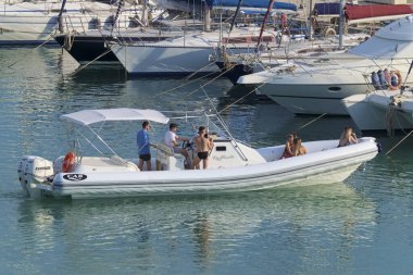 İtalya, Sicilya, Akdeniz, Marina di Ragusa (Ragusa Eyaleti); 6 Temmuz 2020, limandaki kauçuk tekne ve lüks yatlarda yaşayan insanlar - EDITORIAL