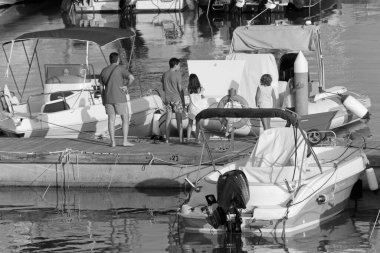 İtalya, Sicilya, Akdeniz, Marina di Ragusa (Ragusa ili); 13 Temmuz 2020, limanda insanlar ve motorlu tekneler - EDITORIAL