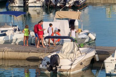 İtalya, Sicilya, Akdeniz, Marina di Ragusa (Ragusa ili); 13 Temmuz 2020, limanda insanlar ve motorlu tekneler - EDITORIAL