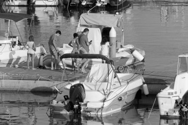 İtalya, Sicilya, Akdeniz, Marina di Ragusa (Ragusa ili); 13 Temmuz 2020, limanda insanlar ve motorlu tekneler - EDITORIAL