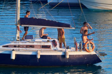 İtalya, Sicilya, Akdeniz, Marina di Ragusa (Ragusa ili); 20 Temmuz 2020, limandaki bir yelkenli teknesinde insanlar - EDITORIAL