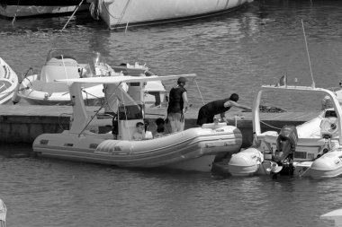 İtalya, Sicilya, Akdeniz, Marina di Ragusa (Ragusa Eyaleti); 25 Temmuz 2020, limandaki kauçuk bir teknede insanlar - EDITORIAL