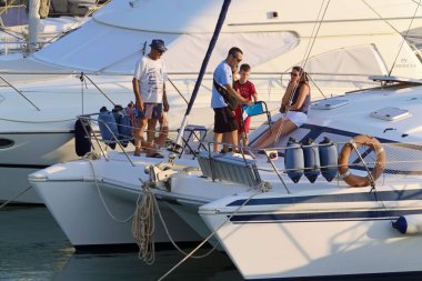 İtalya, Sicilya, Akdeniz, Marina di Ragusa (Ragusa Eyaleti); 11 Ağustos 2020, limandaki bir yelkenli ve lüks yatlarda yaşayan insanlar - EDITORIAL