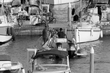 İtalya, Sicilya, Akdeniz, Marina di Ragusa (Ragusa Eyaleti); 15 Ağustos 2020, büyük bir kauçuk bot ve limandaki lüks yatlarda yaşayan insanlar - EDITORIAL