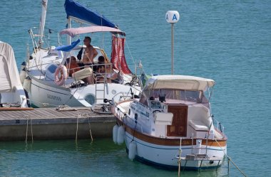 İtalya, Sicilya, Akdeniz, Marina di Ragusa (Ragusa Eyaleti); 18 Ağustos 2020, limandaki bir yelkenli ve lüks yatlarda yaşayan insanlar - EDITORIAL