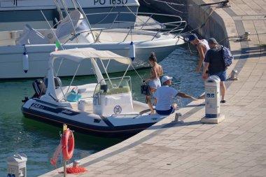 İtalya, Sicilya, Akdeniz, Marina di Ragusa (Ragusa Eyaleti); 19 çirkin 2020, limandaki kauçuk tekne ve lüks yatlarda yaşayan insanlar - EDITORIAL