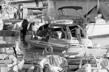 İtalya, Sicilya, Akdeniz, Marina di Ragusa (Ragusa Eyaleti); 20 Ağustos 2020, büyük bir kauçuk bot ve limandaki lüks yatlarda yaşayan insanlar - EDITORIAL