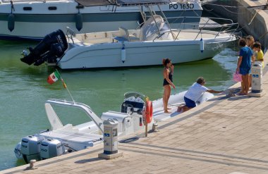 İtalya, Sicilya, Akdeniz, Marina di Ragusa (Ragusa ili); 22 Ağustos 2020, limandaki kauçuk bir tekne ve lüks yatlarda yaşayan insanlar - EDITORIAL