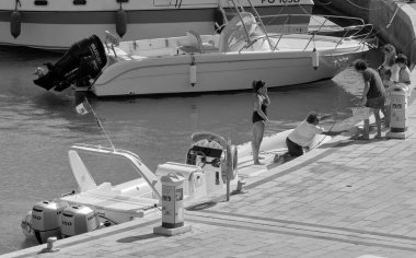 İtalya, Sicilya, Akdeniz, Marina di Ragusa (Ragusa ili); 22 Ağustos 2020, limandaki kauçuk bir tekne ve lüks yatlarda yaşayan insanlar - EDITORIAL