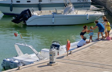 İtalya, Sicilya, Akdeniz, Marina di Ragusa (Ragusa ili); 22 Ağustos 2020, limandaki kauçuk bir tekne ve lüks yatlarda yaşayan insanlar - EDITORIAL