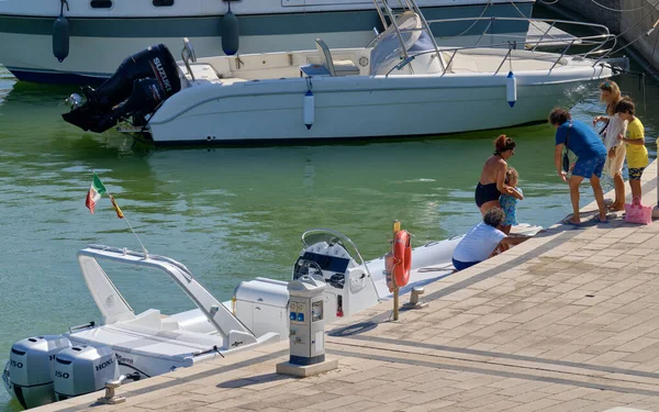 İtalya, Sicilya, Akdeniz, Marina di Ragusa (Ragusa ili); 22 Ağustos 2020, limandaki kauçuk bir tekne ve lüks yatlarda yaşayan insanlar - EDITORIAL