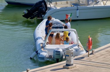 İtalya, Sicilya, Akdeniz, Marina di Ragusa (Ragusa ili); 22 Ağustos 2020, limandaki kauçuk bir tekne ve lüks yatlarda yaşayan insanlar - EDITORIAL