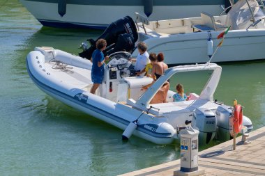 İtalya, Sicilya, Akdeniz, Marina di Ragusa (Ragusa ili); 22 Ağustos 2020, limandaki kauçuk bir tekne ve lüks yatlarda yaşayan insanlar - EDITORIAL