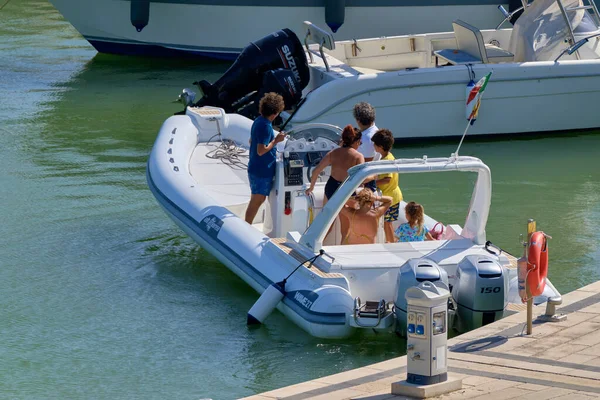 İtalya, Sicilya, Akdeniz, Marina di Ragusa (Ragusa ili); 22 Ağustos 2020, limandaki kauçuk bir tekne ve lüks yatlarda yaşayan insanlar - EDITORIAL