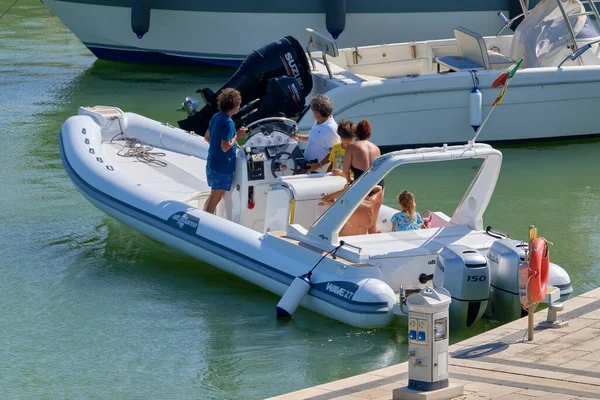 İtalya, Sicilya, Akdeniz, Marina di Ragusa (Ragusa ili); 22 Ağustos 2020, limandaki kauçuk bir tekne ve lüks yatlarda yaşayan insanlar - EDITORIAL