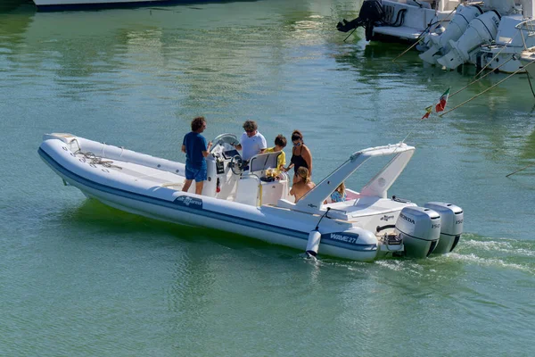 İtalya, Sicilya, Akdeniz, Marina di Ragusa (Ragusa ili); 22 Ağustos 2020, limandaki kauçuk bir tekne ve lüks yatlarda yaşayan insanlar - EDITORIAL