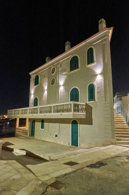 İtalya, Sicilya, Akdeniz, Punta Secca (Ragusa Eyaleti), geceleri deniz kenarında eski bir Sicilya taş evinin cephesi.