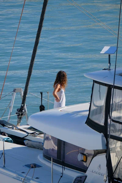 İtalya, Sicilya, Akdeniz, Marina di Ragusa (Ragusa Eyaleti); limandaki katamaran yelkenli teknesinde bir kadın 