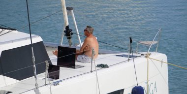 Italy, Sicily, Mediterranean Sea, Marina di Ragusa (Ragusa Province); 10 September 2025, man on a catamaran sailing boat in the port - EDITORIAL