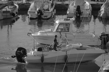 İtalya, Sicilya, Akdeniz, Marina di Ragusa (Ragusa Eyaleti); 14 Eylül 2025, limandaki motorlu teknelerde erkekler - EDITORIAL