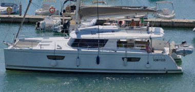 İtalya, Sicilya, Akdeniz, Marina di Ragusa (Ragusa Eyaleti); 14 Eylül 2025, limandaki katamaran yelkenli teknesinde insanlar - EDITORIAL