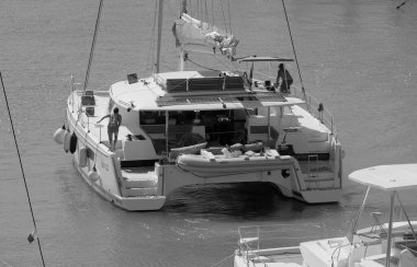 İtalya, Sicilya, Akdeniz, Marina di Ragusa (Ragusa Eyaleti); 14 Eylül 2025, limandaki katamaran yelkenli teknesinde insanlar - EDITORIAL