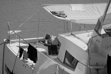 İtalya, Sicilya, Akdeniz, Marina di Ragusa (Ragusa Eyaleti); 23 Eylül 2025, limandaki bir katamaran yelkenli teknesinde adam - EDITORIAL