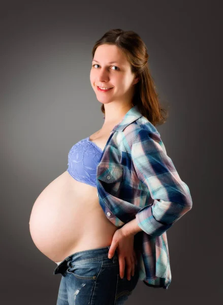 Mujer embarazada sobre fondo gris — Foto de Stock