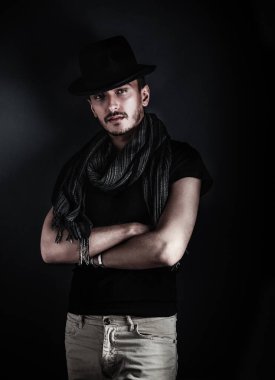 Yakışıklı genç adam poz ile mavi arka plan üzerinde bir şapka. Vintage tarzı resim tonda.