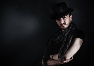 Yakışıklı genç adam poz ile mavi arka plan üzerinde bir şapka. Vintage tarzı resim tonda.