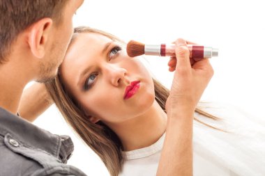 Makyaj uygulamak. Toz uygulama makyöz. Beyaz arka plan üzerinde izole. Stüdyo çekimi.