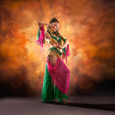 Geleneksel bellydance bir kostümle renkli stüdyo arka plan üzerinde dans muhteşem bir kadın bellydancer.