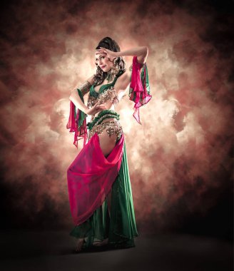 Geleneksel bellydance bir kostümle renkli stüdyo arka plan üzerinde dans muhteşem bir kadın bellydancer.