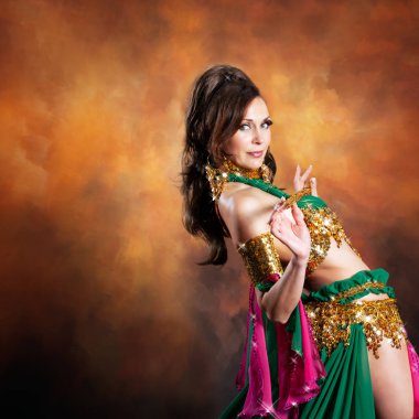 Geleneksel bellydance bir kostümle renkli stüdyo arka plan üzerinde dans muhteşem bir kadın bellydancer.