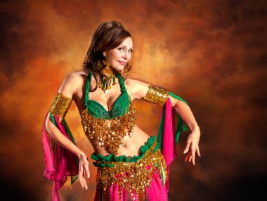 Geleneksel bellydance bir kostümle renkli stüdyo arka plan üzerinde dans muhteşem bir kadın bellydancer.