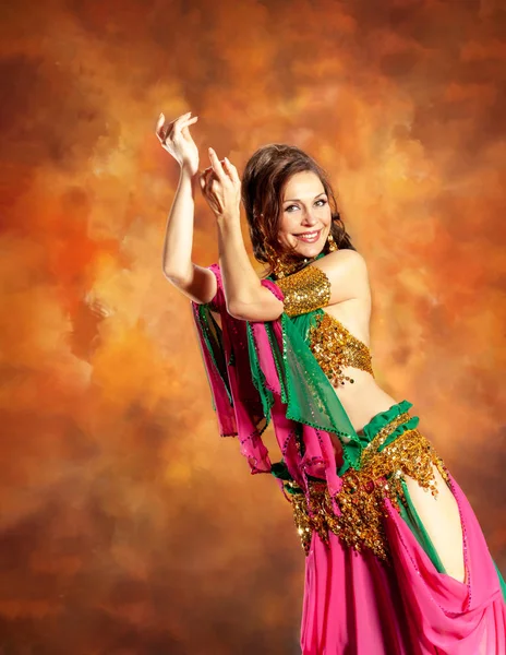 Prachtige vrouw buikdanseres dansen in traditionele buikdansen kostuum over gekleurde studio achtergrond. — Stockfoto