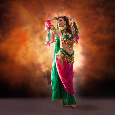 Geleneksel bellydance bir kostümle renkli stüdyo arka plan üzerinde dans muhteşem bir kadın bellydancer.